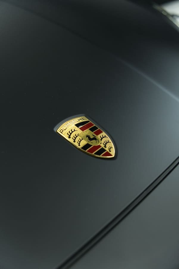 Escudo Porsche dorado sobre el capó negro satinado del Cayenne