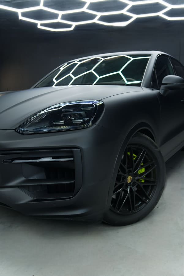 Porsche Cayenne con Car Wrap negro satinado, tres cuartos delantero con pinzas de freno verde ácido