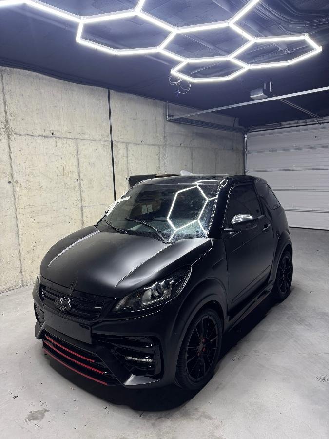 Microcoche Ligier con Car Wrap negro mate, tres cuartos delantero bajo luces hexagonales