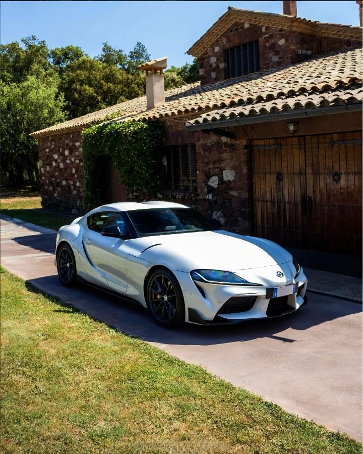 White Toyota GR Supra parked by a Catalan stone masia