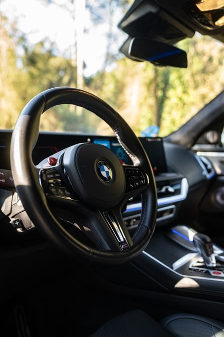 BMW XM cockpit and M steering wheel with woodland behind